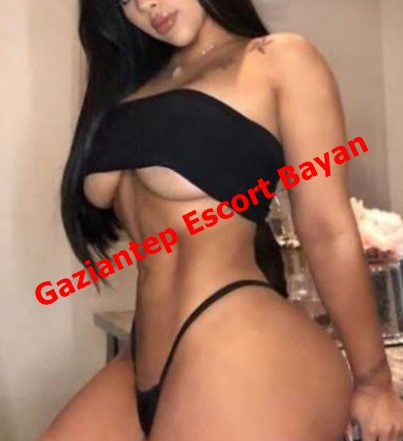 Woman in a black bandeau top and thong bikini posing in a room; red watermark 'Gaziantep Escort Bayan' across her torso.